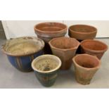 7 terracotta and glazed garden plant pots in varying sizes. 2 in a hexagonal shape.