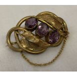 A Victorian style pinchbeck brooch with leaf detail, set with 3 oval cut amethyst stones.