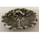 An Art Nouveau style white metal pin dish in the shape of a leaf with a nude figure in relief.