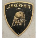 A cast iron black and gold painted shield shaped "Lamborghini" wall plaque.