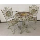 A decorative circular metal garden table and 2 chairs painted pale green.