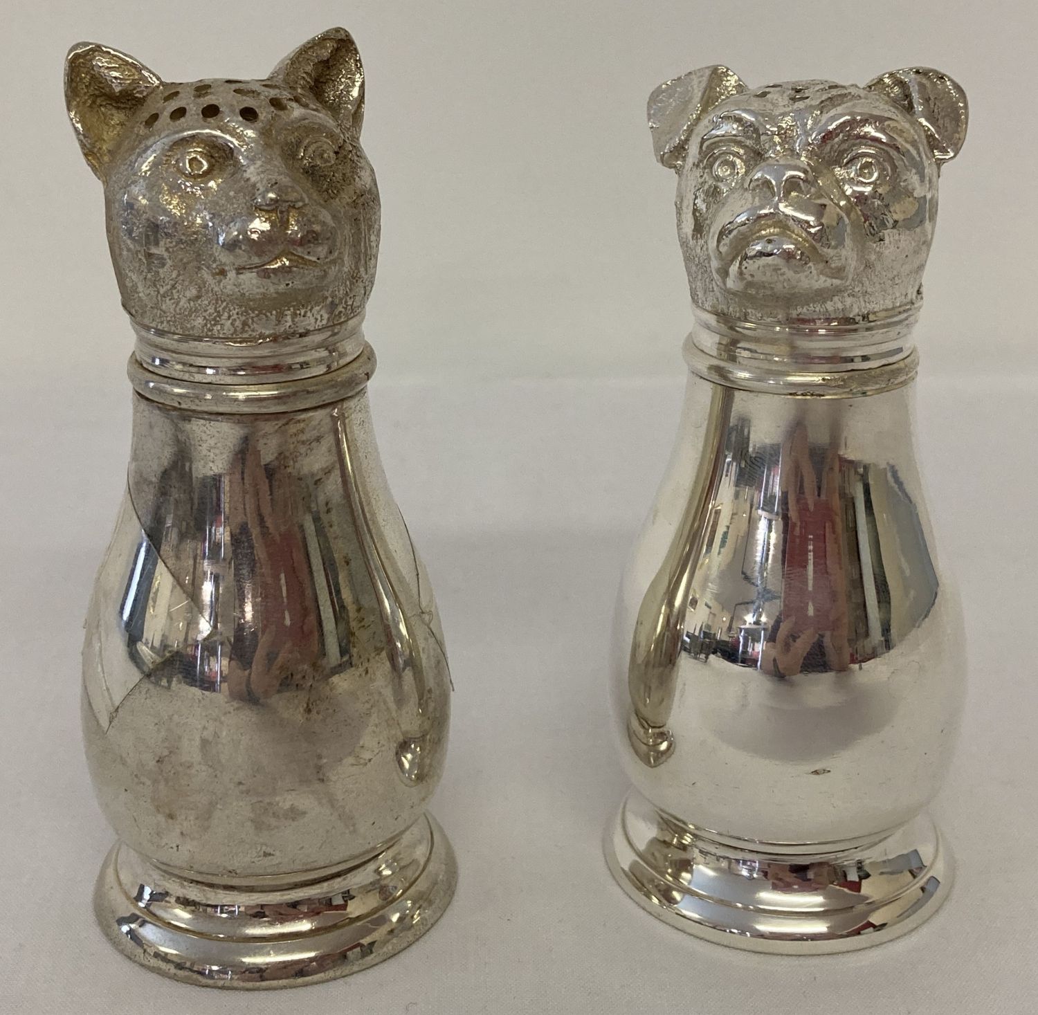 A silver plated novelty cruet with shakers in the form of cat and dog heads.