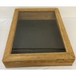 A light wood table top display case with faux leather to interior.
