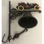 A cast iron wall hanging garden bell with painted veteran car detail.