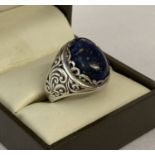 A silver and oval cut lapis lazuli dress ring. Pierced scroll detail to both sides.