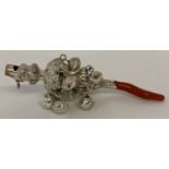 A decorative white metal babies rattle with whistle and coral handle/teether.