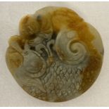 A Chinese Jade roundel depicting a figure riding a dragon. Carved detail to both side.