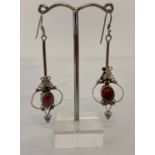 A pair of Art Nouveau style silver drop earrings set with garnet cabochon stones.