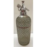 A 1930's Sparklets soda syphon with wire mesh covering.