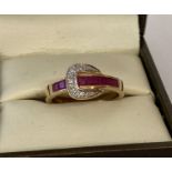 A 9ct gold ruby and diamond set buckle design dress ring, possibly Luke Stockley, London.
