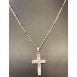 A boxed silver cross pendant set with clear baguette cut stones on a decorative 16" curb chain.