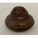 A small circular wooden Japanese trinket pot with carved figural detail to top.