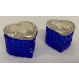 A pair of cut blue glass heart shaped trinket pots with decorative sterling silver lids.