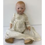 An Armand Marseille bisque head baby doll on composition body in cotton gown.