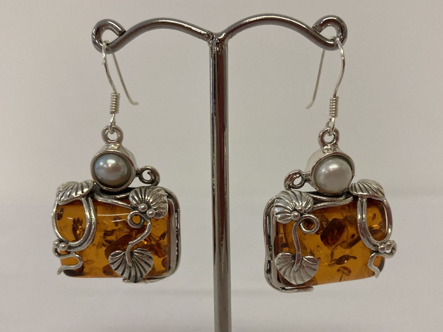 A pair of silver mounted Art Nouveau style drop earrings set with amber and pearl.