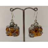 A pair of silver mounted Art Nouveau style drop earrings set with amber and pearl.