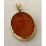 A carved oval carnelian pendant depicting a coat of arms in a 9ct gold mount.