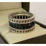 A heavy silver full eternity style band ring set with baguette cut black stones.