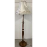 A modern dark wood standard lamp with carved channelled detail.