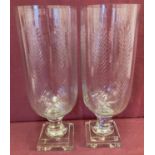 A pair of cut glass vases raised on pedestal stems with engraved detail.