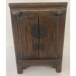 A dark wood small table top oriental style 2 door cabinet. With interior shelf and small drawer.