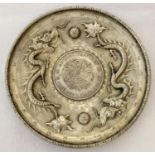 A Chinese white metal coin dish, made from central coin with white metal surround featuring dragons.