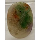 A carved jade oval shaped pendant featuring a tiger.