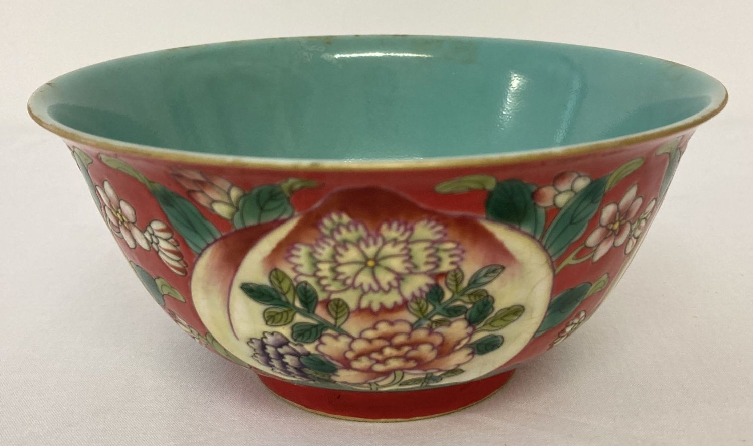 A Chinese ceramic bowl with decorative outer bowl and blue/green glaze interior.