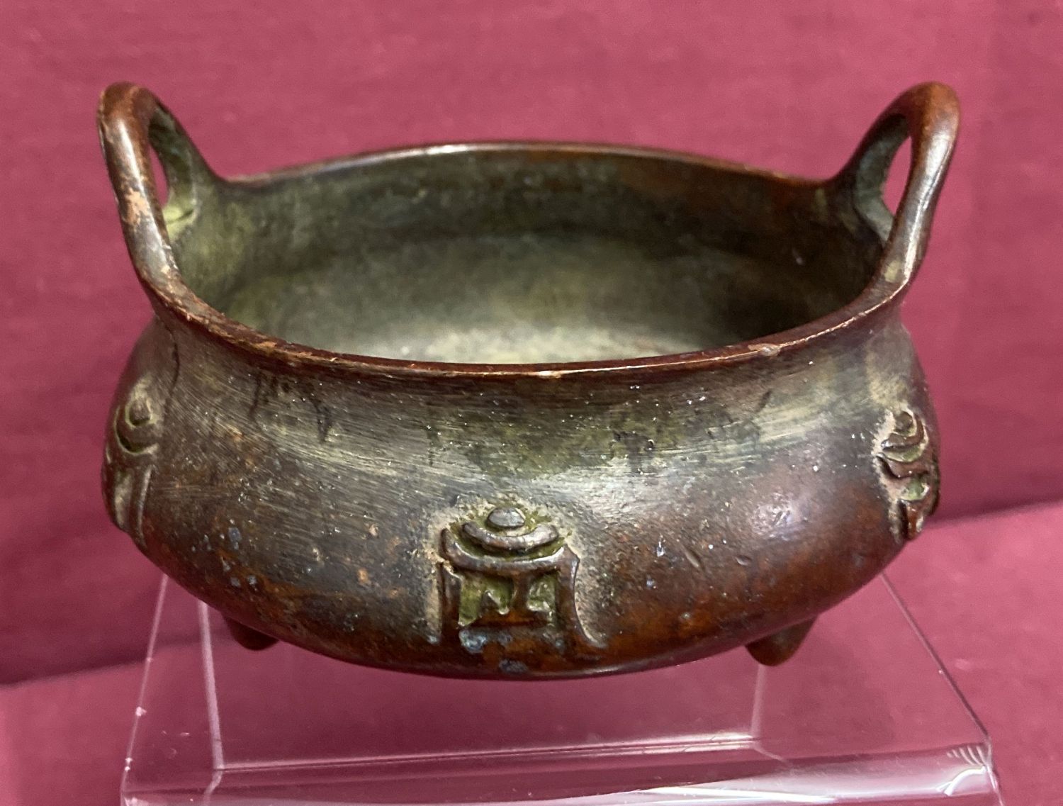 A small bronze 2 handled censer, raised on tripod feet & with calligraphy detail to outer bowl.