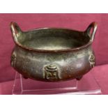 A small bronze 2 handled censer, raised on tripod feet & with calligraphy detail to outer bowl.