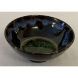 A small black glaze ceramic tea bowl with drip glaze detail & green crystalline glaze to inner bowl.