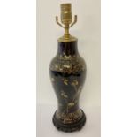 A black ceramic table lamp base with painted gold floral detail.