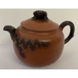 A brown and orange glaze terracotta teapot with cherry blossom detail and frog shaped finial to lid.