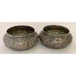 2 small white metal decorative bowls with ornate floral carved detail throughout.