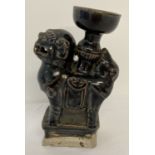 A Chinese stoneware ceramic candle holder in the form of a foo dog, with black glaze.