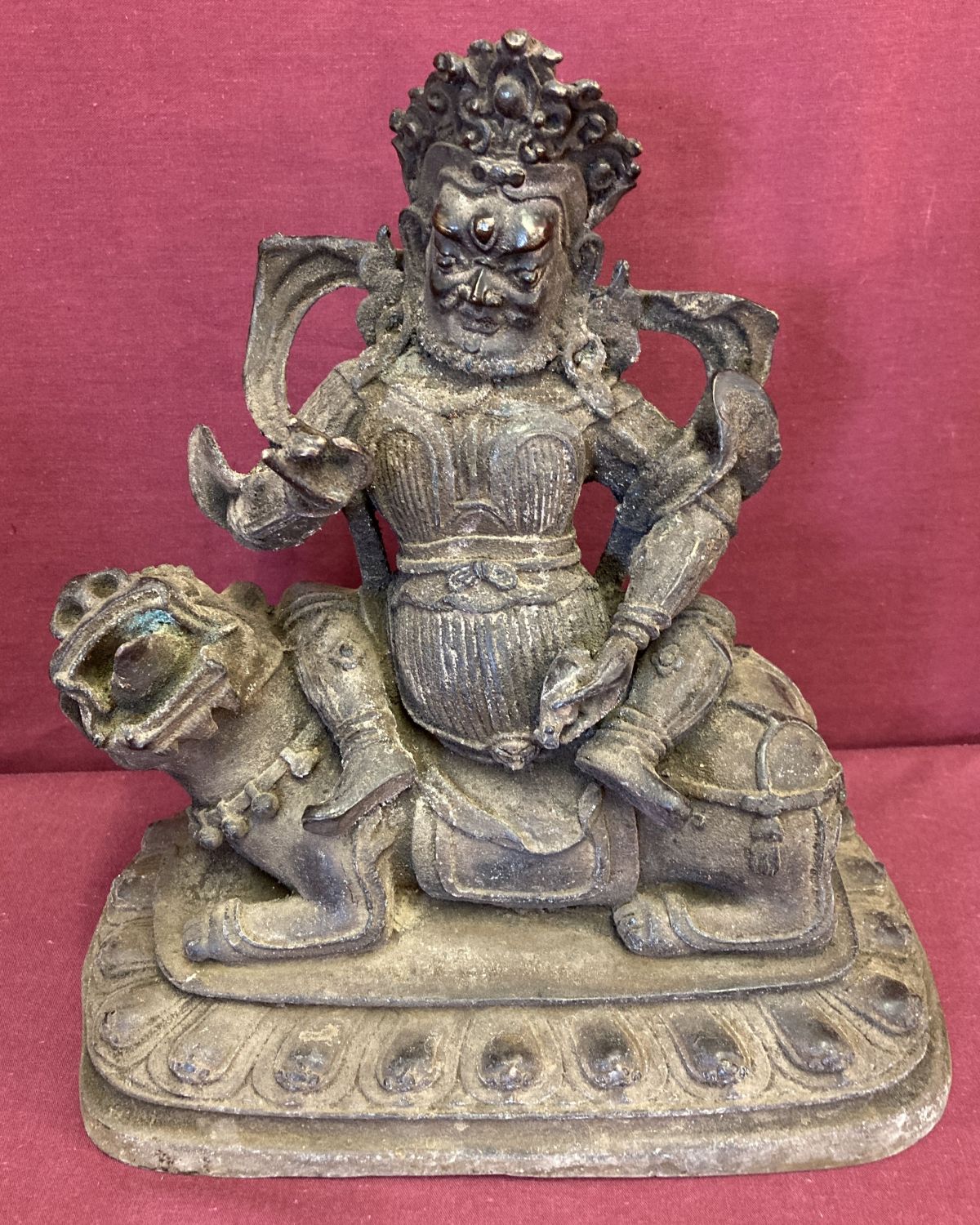 A large hollow bronze figurine of an Oriental Deity sitting atop a Foo dog.