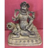 A large hollow bronze figurine of an Oriental Deity sitting atop a Foo dog.