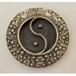 A Chinese white metal ink stone in the form of yin and yang bordered by a floral design.
