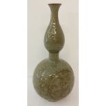 A large double gourd shaped, celadon glaze vase with floral decoration.