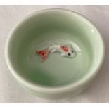 A small pale green glazed ceramic bowl with fish detail, in relief, to base of interior.