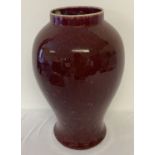 A large ceramic sang de boeuf glazed vase of bulbous form.