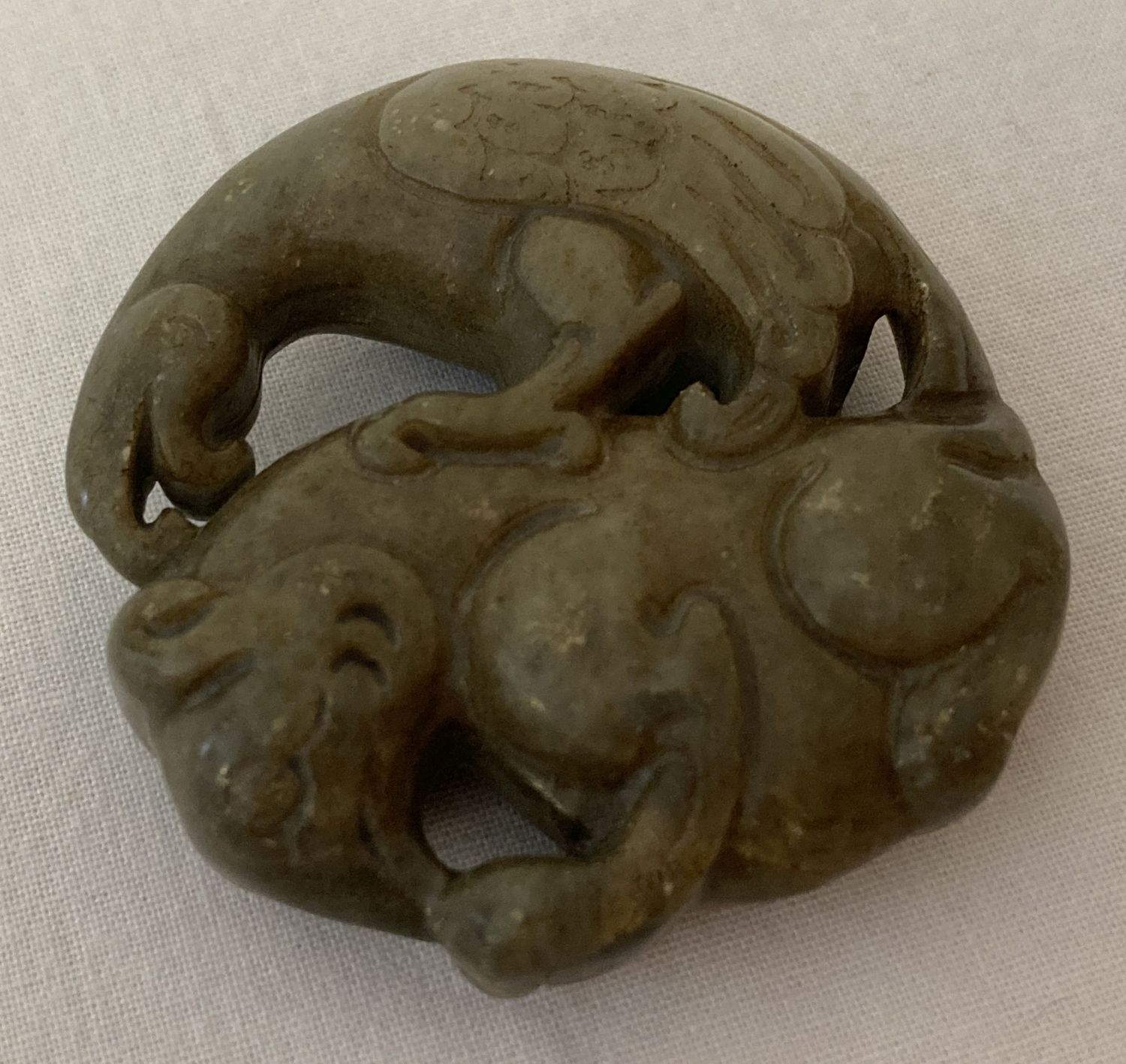 A Chinese Jade roundel depicting Mythical creatures. Carved detail to both side.