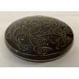 A black glazed Chinese porcelain lidded shallow dish, with raised floral detail to lid.