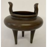 A Chinese bronze censer raised on tall tapered tripod feet & with shaped loop handles.