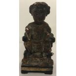 A small painted wooden figure of a oriental deity with gilt detail.