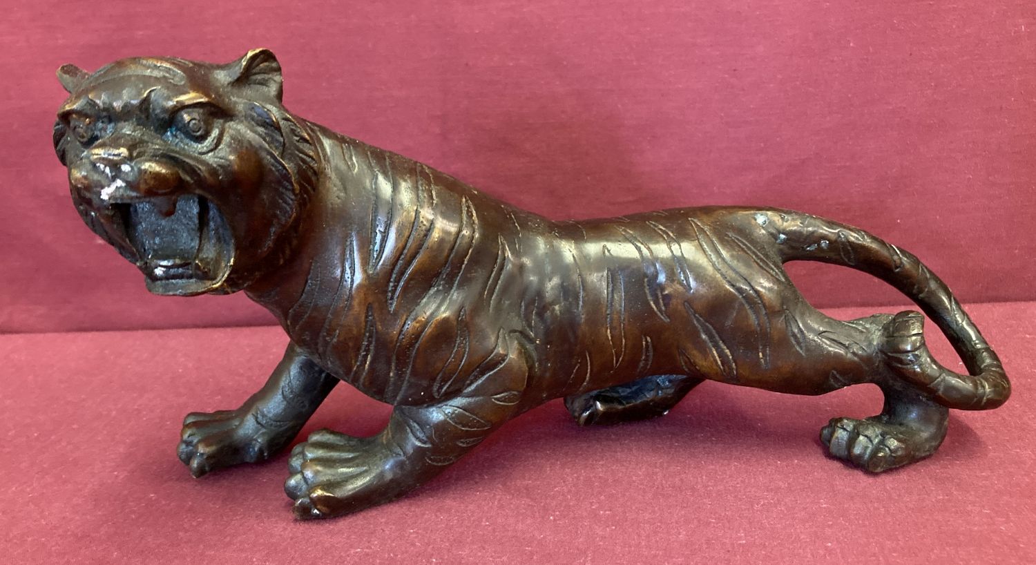 A hollow bronze figurine of a roaring tiger.