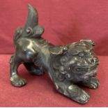 A hollow bronze figurine of a foo dog.