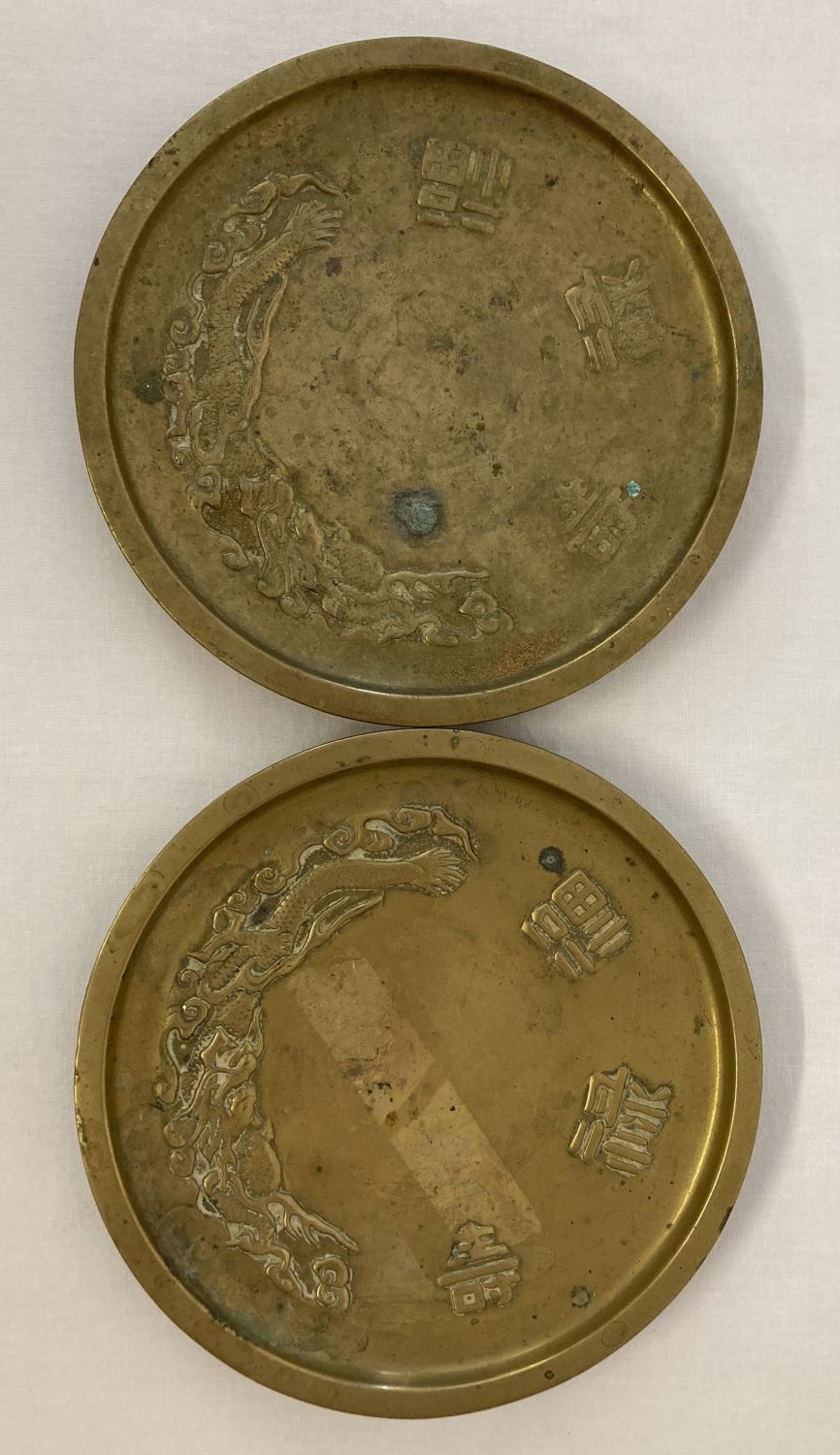 2 Chinese brass circular shaped dishes with dragon detail and Chinese symbols.