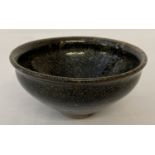 A small ceramic bowl with black hares fur style glaze.