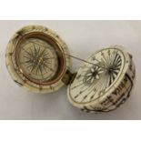 A carved bone scrimshaw style globe with hinged lid and compass inset to interior.